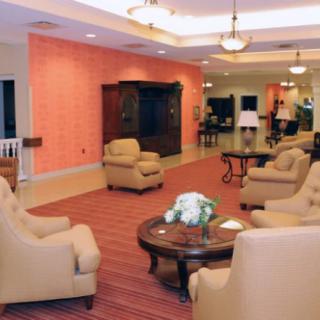 A cozy lobby with comfortable armchairs and a central coffee table, illuminated by warm lighting.
