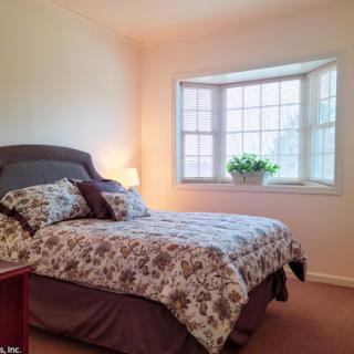 A cozy bedroom featuring a floral-patterned bedspread and a lovely bay window.