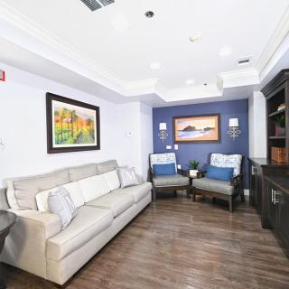 A modern living room featuring a comfortable sofa, armchairs, and elegant artwork on the walls.