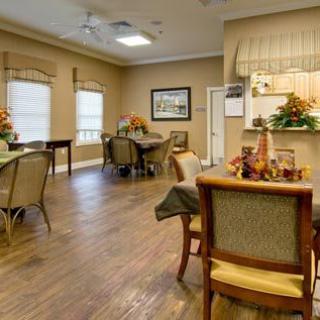 A cozy dining area with multiple tables and chairs, featuring warm decor and wood flooring.