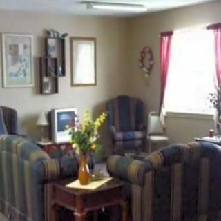 A cozy living room with sofas and chairs arranged around a small table, featuring a vase of flowers.