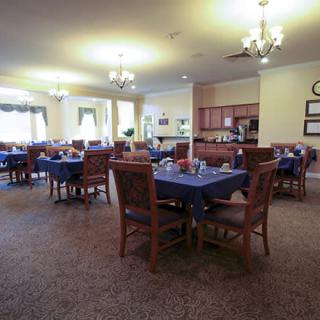 A spacious dining area with neatly arranged tables and chairs, illuminated by elegant chandeliers.