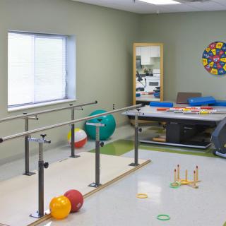 A therapy room equipped with parallel bars and various exercise equipment for rehabilitation purposes.