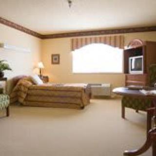 A spacious hotel room with a bed, TV, and seating area.