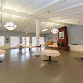 An empty room with tables, chairs, and chandeliers.