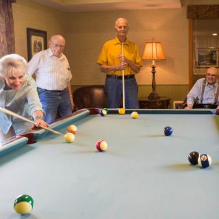 A group of seniors enjoying a game of billiards together.