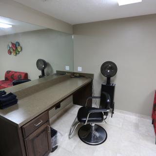 A salon workspace featuring a styling chair, large mirror, and hair dryer.