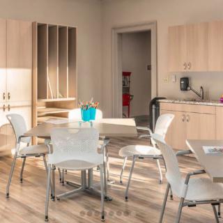A modern kitchen and dining area with light wooden cabinets, a table, and chairs.