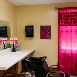 A cozy hair salon interior featuring a waiting area with a mirror, chairs, and vibrant red curtains.