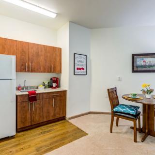 A cozy apartment kitchen with wooden cabinets and a small dining area.