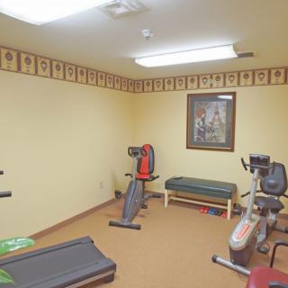 A small gym room with various fitness equipment including a treadmill and an exercise bike.