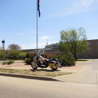 A unique motorcycle display near a building, accompanied by a flag.