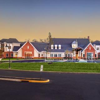 A suburban residential building with a landscaped front and parking area during the evening.