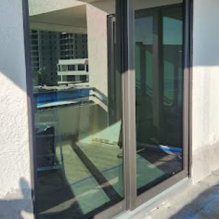 A sliding glass door with reflections showcasing a modern balcony view.