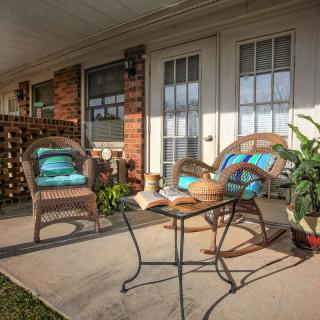A cozy patio setup with wicker chairs, a small table, and potted plants, perfect for relaxation.