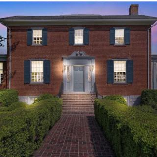 A charming brick house with well-maintained landscaping, illuminated in the evening light.