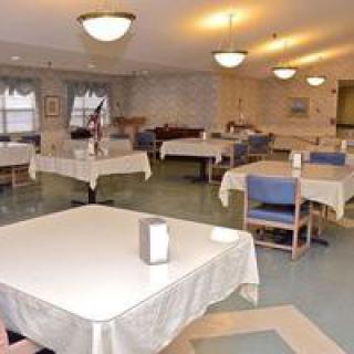 An empty dining room with tables and chairs arranged neatly under bright ceiling lights.