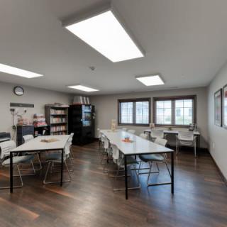 A spacious classroom with desks, chairs, and large windows.