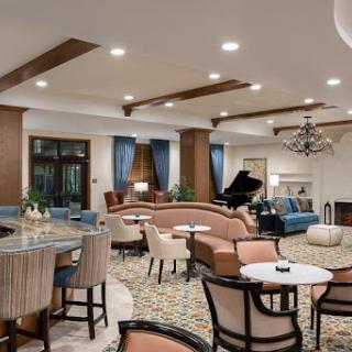 A stylish and inviting lounge area featuring comfortable seating, a grand piano, and warm lighting.