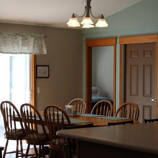 A cozy dining room with wooden chairs and a table under warm lighting.