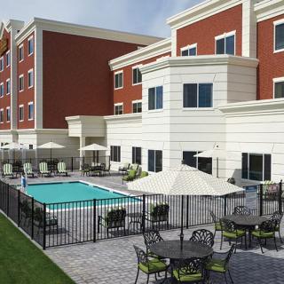 A modern hotel featuring an outdoor swimming pool and seating area with umbrellas.