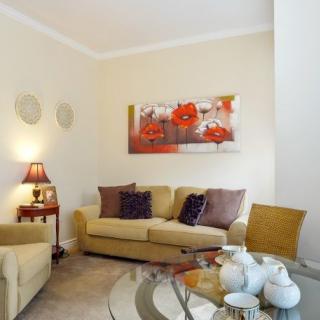 A cozy living room with a sofa, colorful artwork, and a stylish coffee table setup.