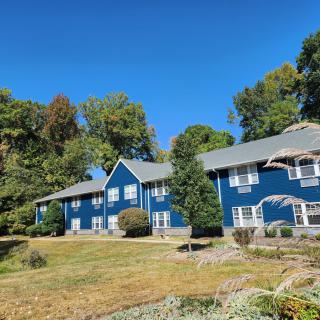 A blue residential building surrounded by greenery on a sunny day.