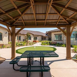 A covered outdoor area with a picnic table overlooking a landscaped garden in a residential setting.