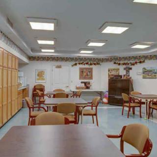 A well-lit room with tables and chairs arranged for dining or meetings.