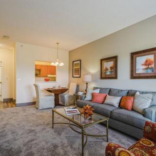 A cozy living room with a plush sofa, coffee table, and adjacent dining area.