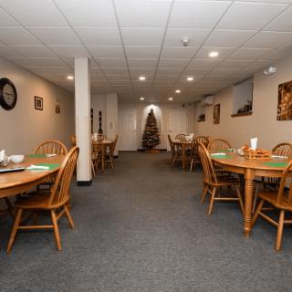 A cozy dining area with wooden tables and chairs, warmly lit and decorated.
