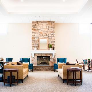 A cozy living room with a central fireplace surrounded by sofas and armchairs.