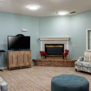A cozy living room with a television and fireplace, featuring comfortable seating and minimalist decor.