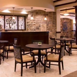 A cozy lobby interior with tables and chairs arranged for seating, featuring modern decor with brick walls and warm lighting.