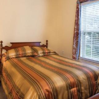 A cozy bedroom with a striped bedspread and a window with blinds.