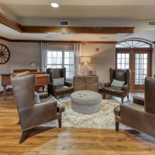 A cozy living room with leather armchairs arranged around a round coffee table on a patterned rug.