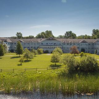 A large building surrounded by a well-maintained lawn and trees under a clear blue sky.