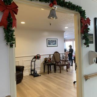 A cozy indoor space adorned with Christmas decorations, featuring a garland and bows around the entrance.