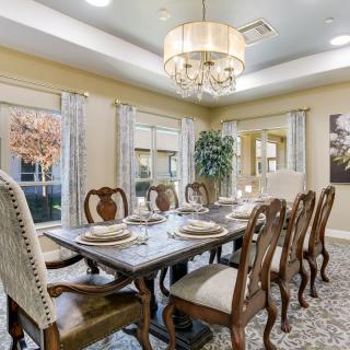 An elegant dining room with a beautifully set table and ornate chairs, illuminated by a stylish chandelier.