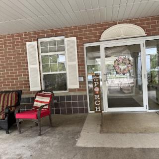 A cozy porch area featuring a welcoming entrance with a red chair and decorative elements.