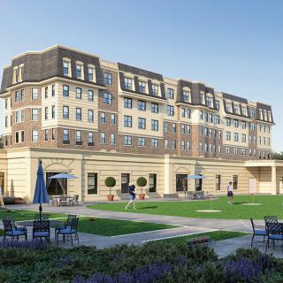 A sunny day view of a large, elegant residential building with well-maintained lawns and outdoor seating.