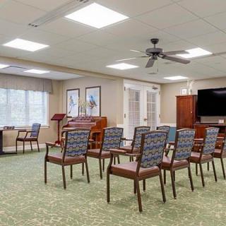 A cozy conference room setup with chairs facing a television and a podium.