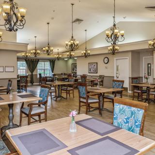 A spacious dining room with elegant chandeliers, neatly arranged tables, and chairs.
