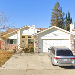A suburban house with a car parked in the driveway.