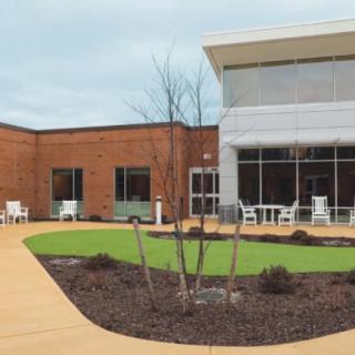 A modern courtyard with seating and landscaping outside a brick building.