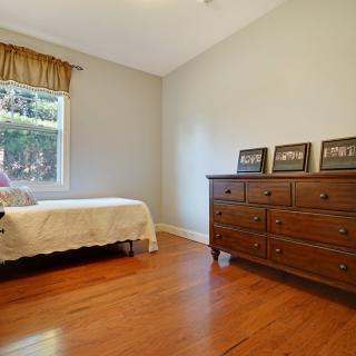 A minimalist bedroom with wooden floors and furniture, including a bed and dresser.