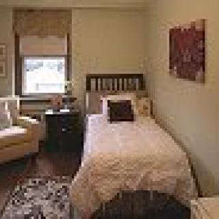 A cozy bedroom with a single bed and an armchair by the window.