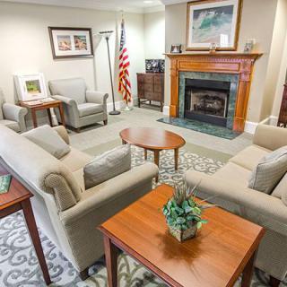 A cozy living room featuring sofas, a fireplace, and elegant decor with an American flag in the corner.