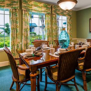 A elegantly set dining room table with chairs and colorful curtains in a well-decorated home.