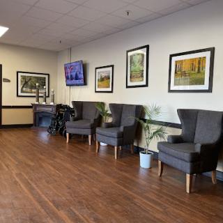 A cozy waiting area featuring comfortable chairs, decorative artwork, and a television.